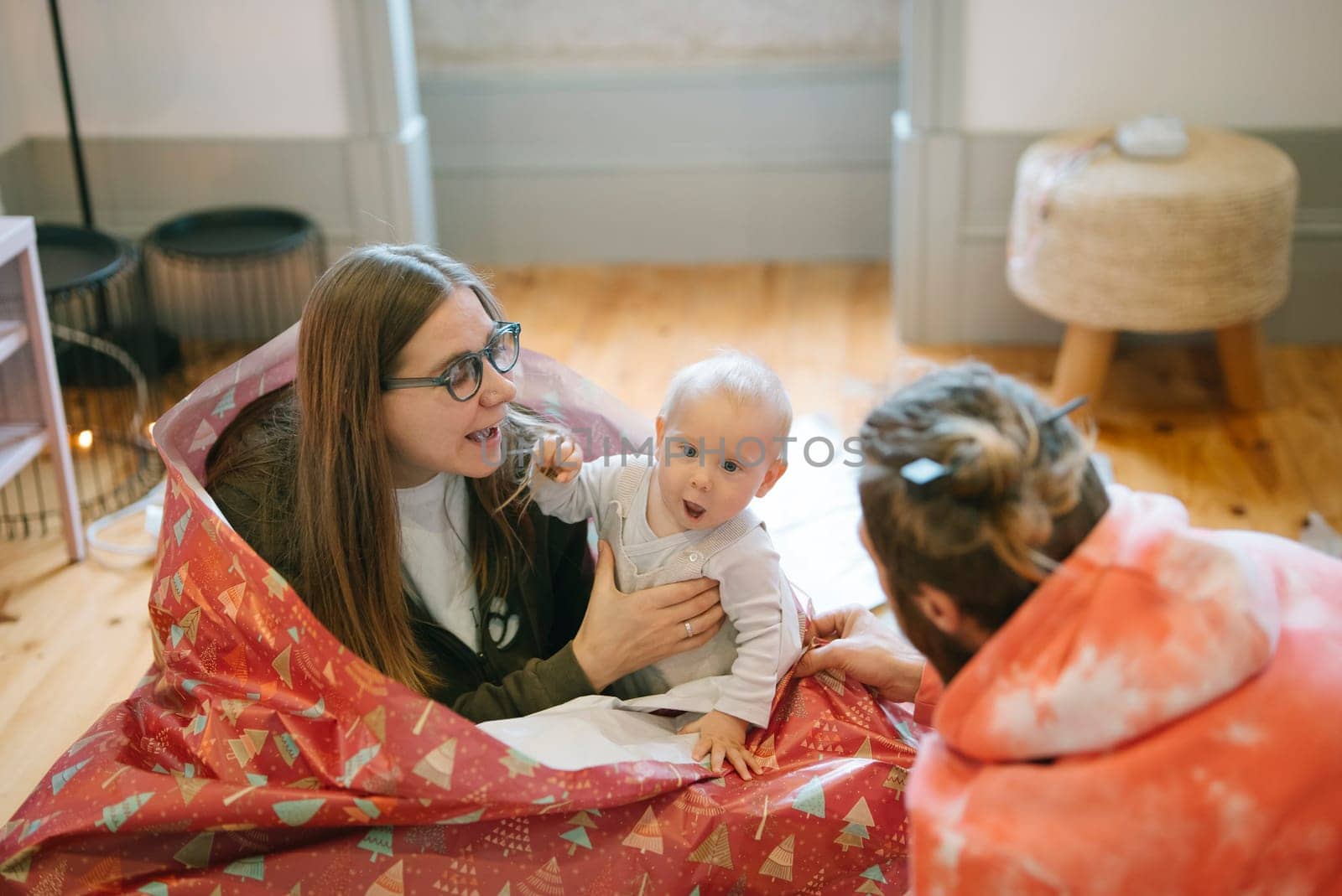 A heartwarming scene of a loving family playfully interacting with a joyful baby in a cozy, natural setting