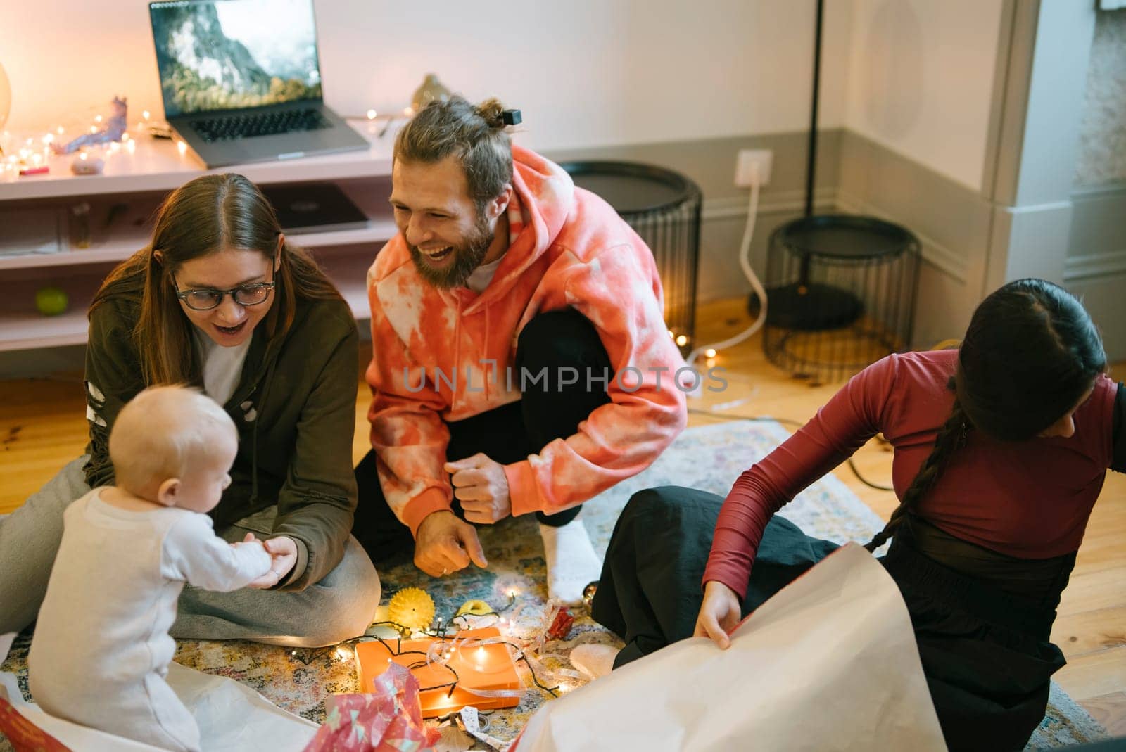 A delightful and joyful family moment featuring a baby, contagious laughter, and giftwrapping during a celebration
