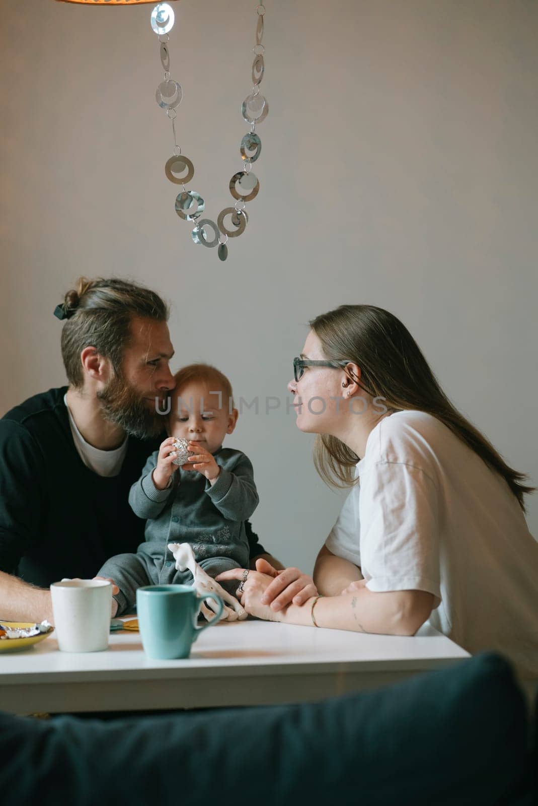 A lovely family is cherishing quality time together in the comfort of their home, enjoying coffee with their baby