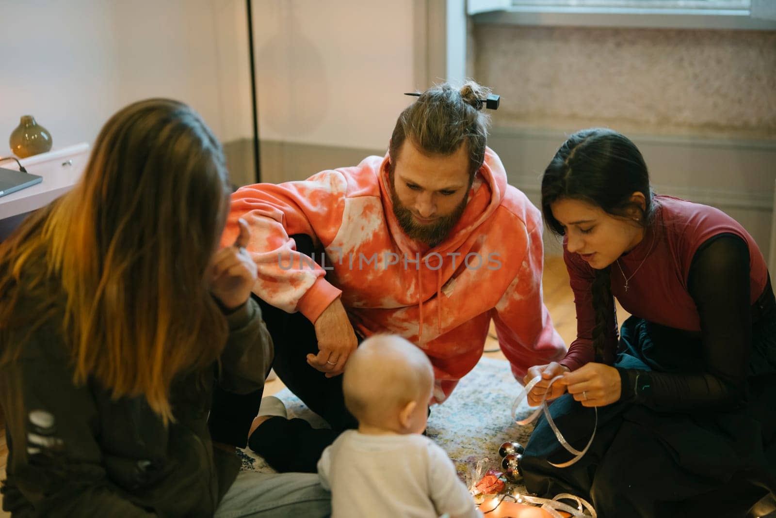 A cheerful group of young adults happily engaging with a cute baby, fostering a warm and loving family atmosphere