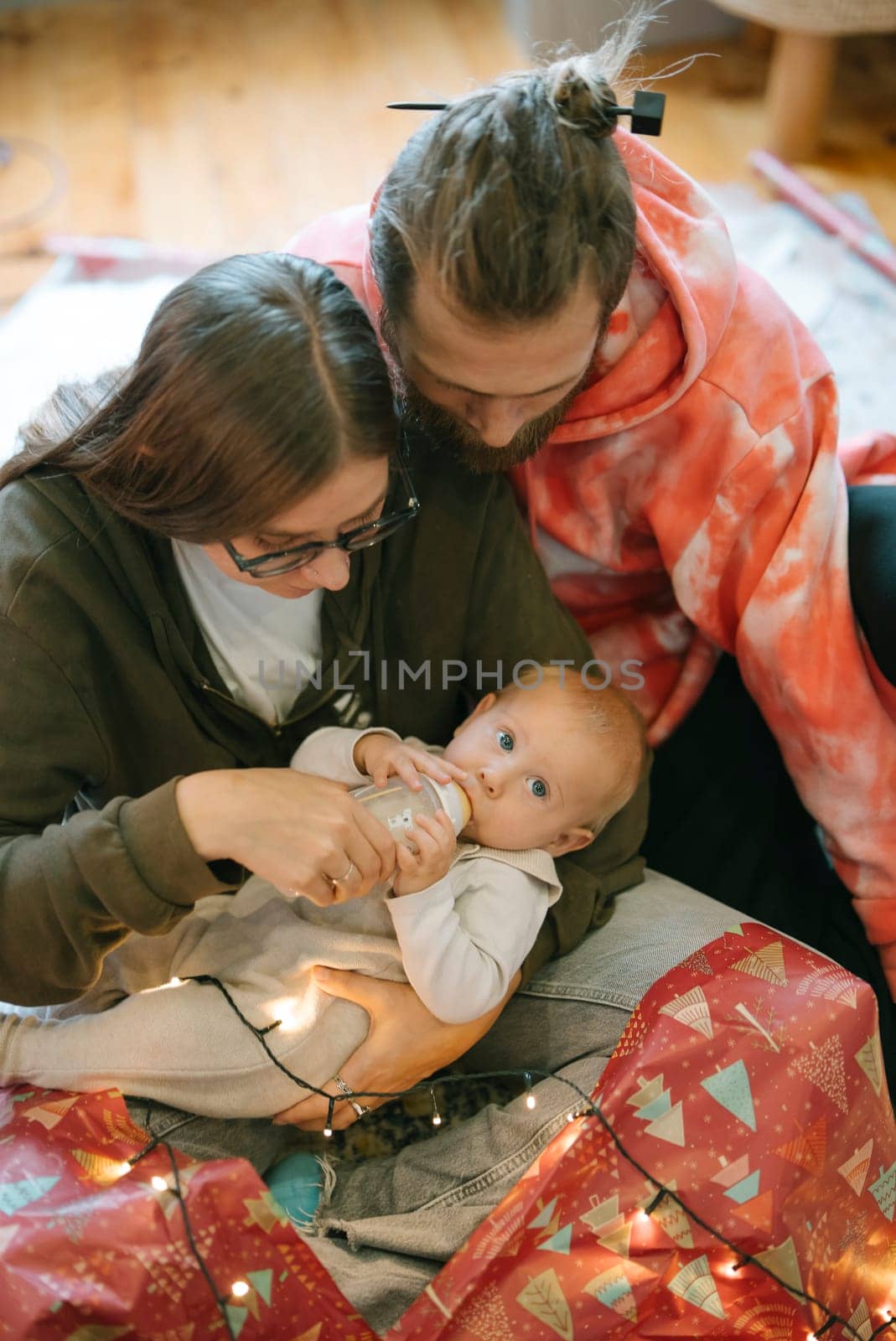 A joyful family enjoys quality time together, with a baby and vibrant festive lights illuminating the scene