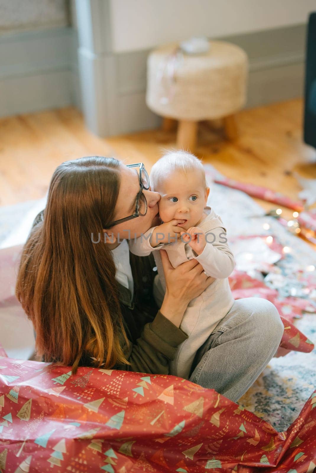 A tender moment unfolds between a loving mother and her adorable baby, surrounded by festive decorations