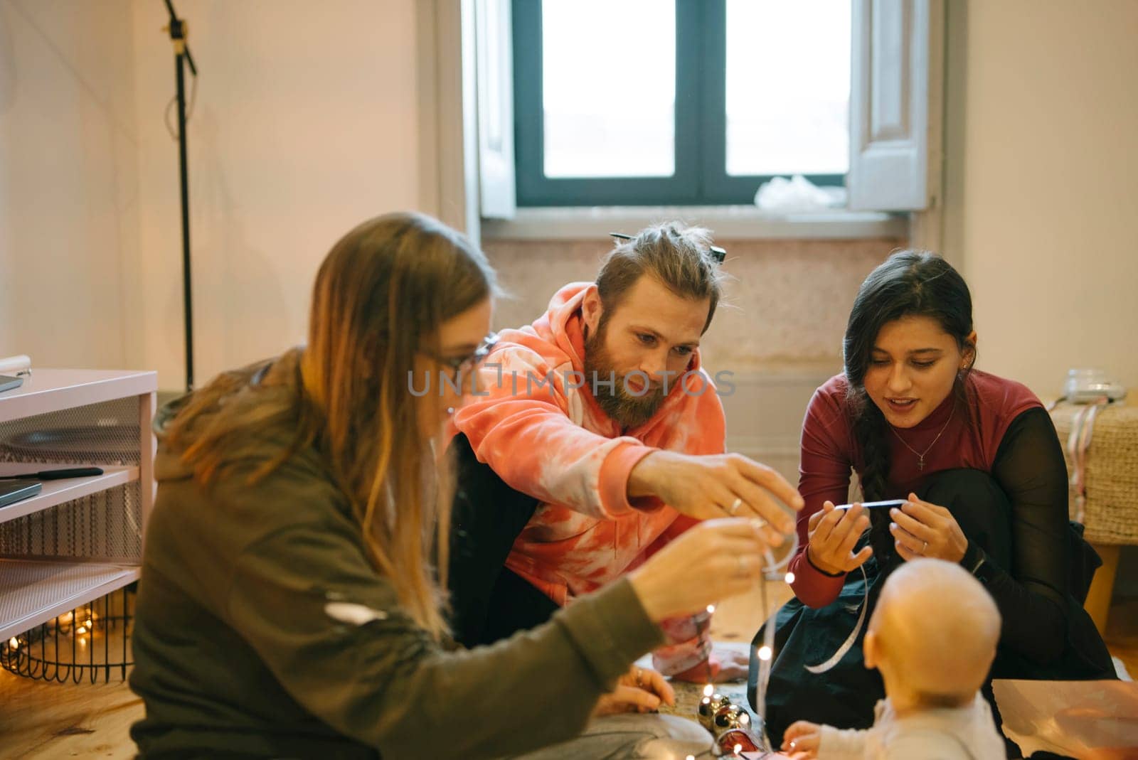 A heartwarming gathering of close friends who are joyfully enjoying quality time spent with a baby indoors