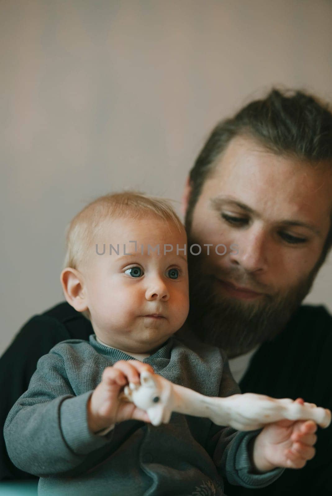 A heartwarming interaction between a loving father and his baby, enjoying a playful moment with a colorful toy