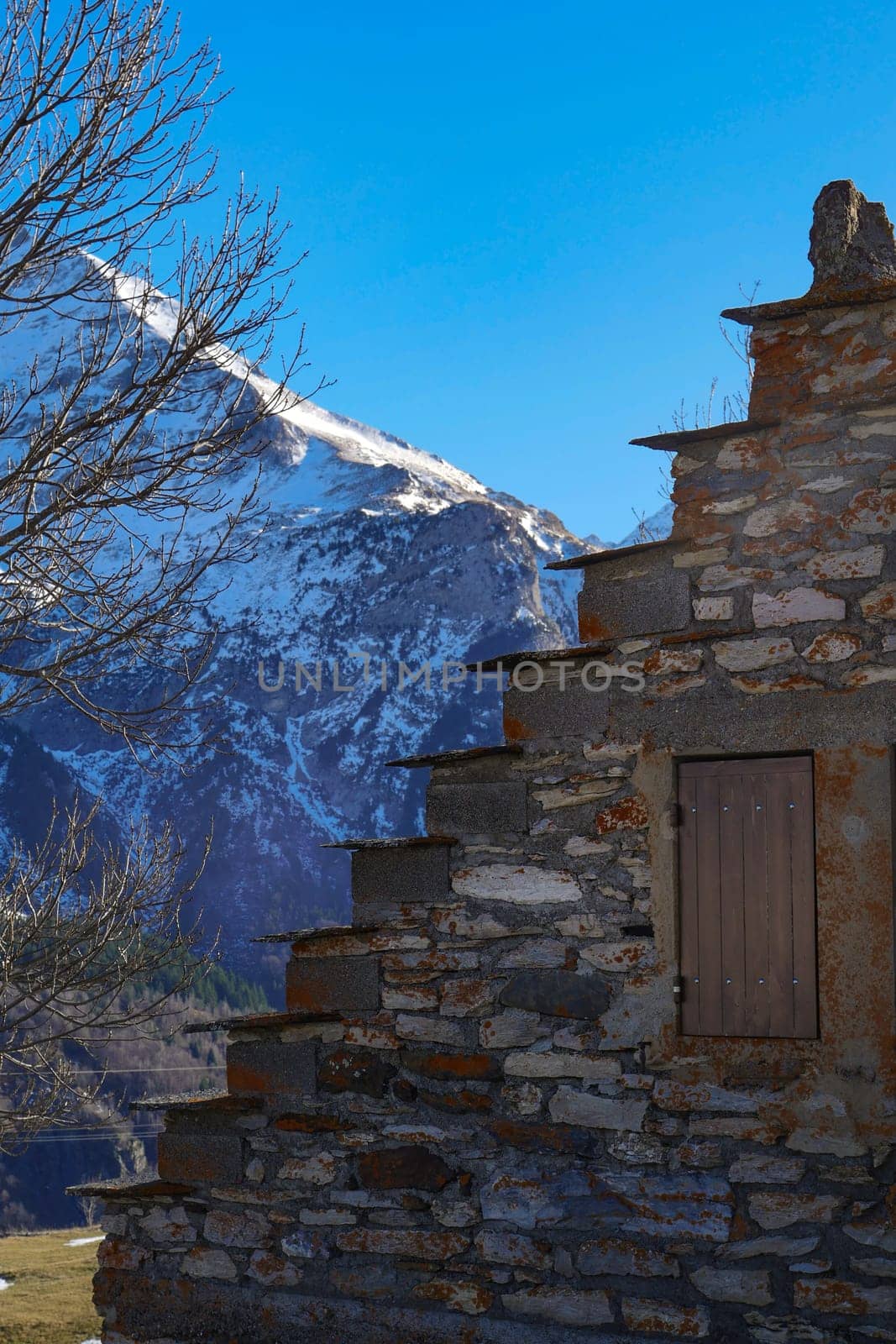 A weathered stone stairway ascends a mountainside, framed by towering peaks and clear blue skies. The scene evokes tranquility and natural beauty.