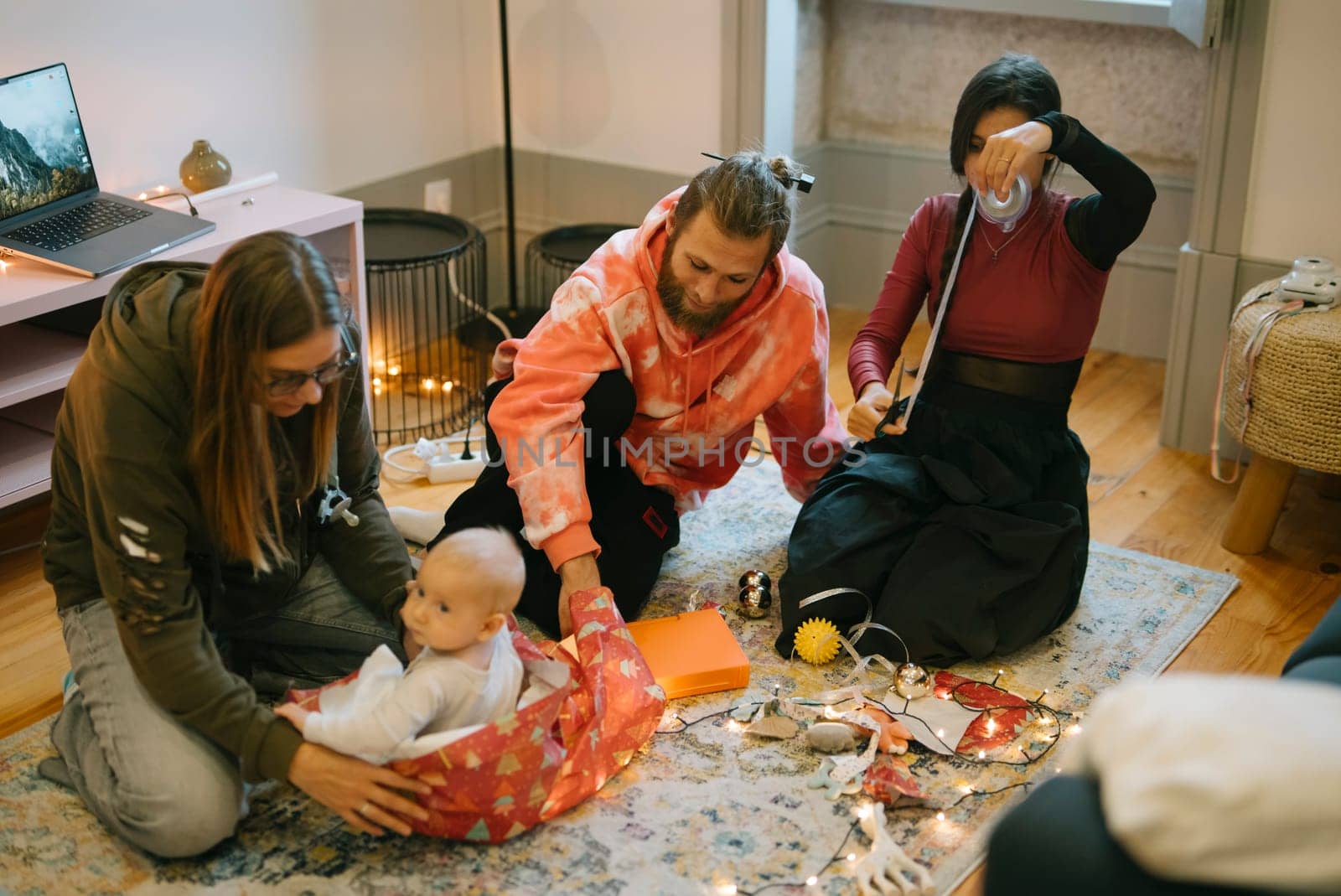A joyful family gathering wraps colorful gifts with a happy baby in a cozy, warm, festive environment