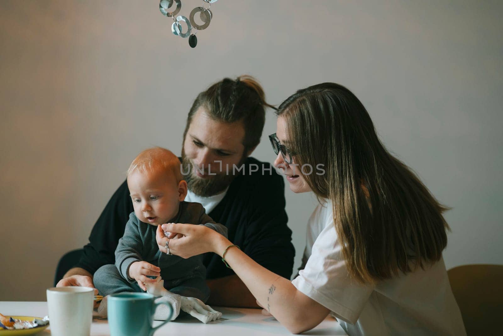 A loving family joyfully shares a delightful moment feeding their adorable little baby at a cozy kitchen table