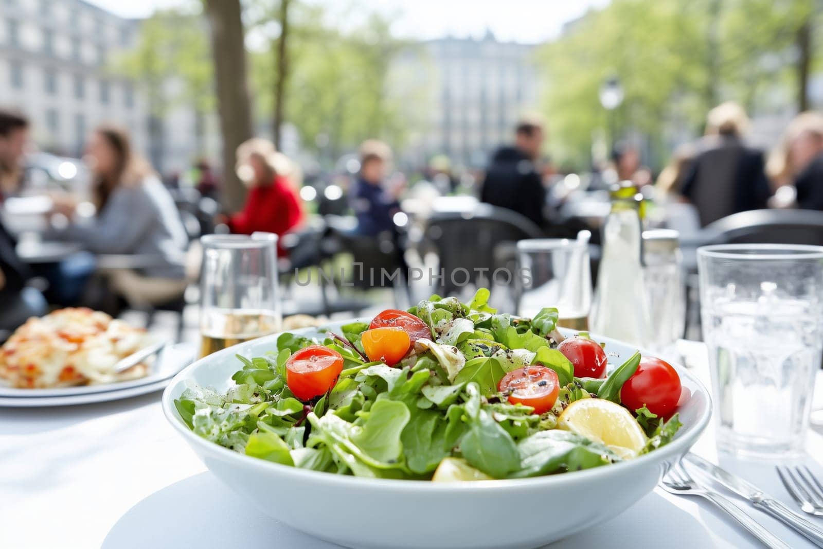 Colorful salad served outdoors with people dining in the background.