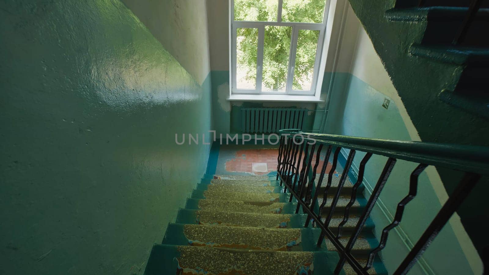 Staircase with chipped paint in an abandoned school building, sunlight streaming through window at the top