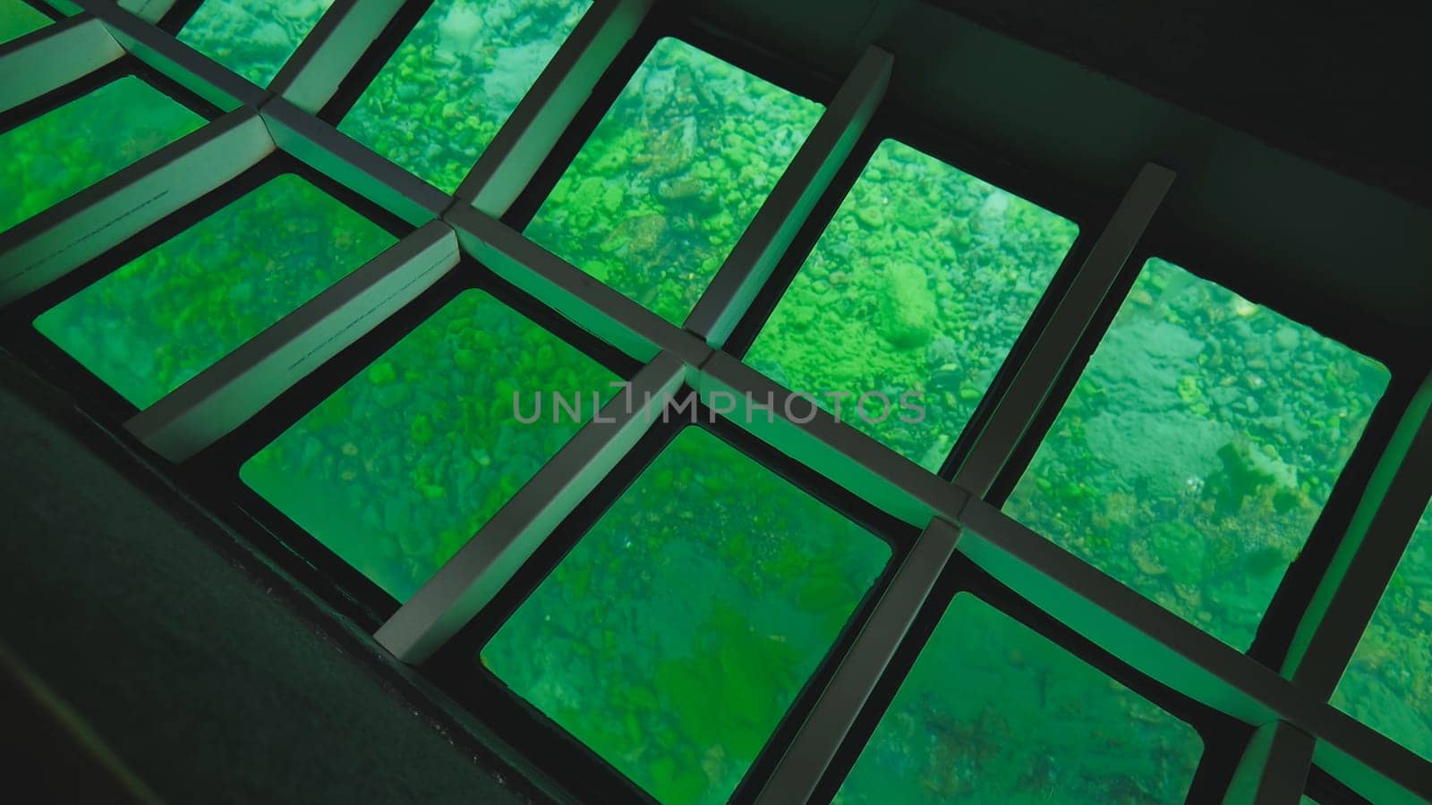 Glass bottom boat revealing emerald green waters, rocky seabed through transparent panels, showcasing vibrant underwater marine landscape