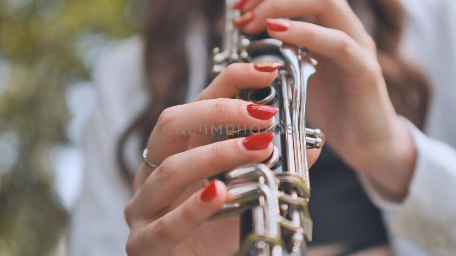 Close up of a musician's hands playing a clarinet outdoors, showcasing the intricate details of the instrument and the musician's skill