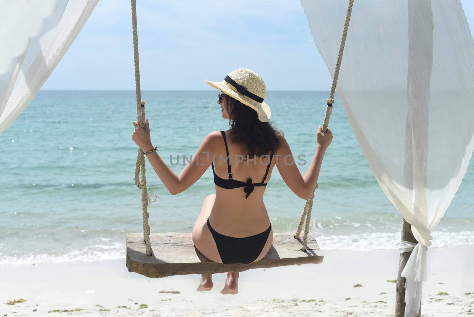 Young woman rides on a swing at Doc Let beach of Vietnam