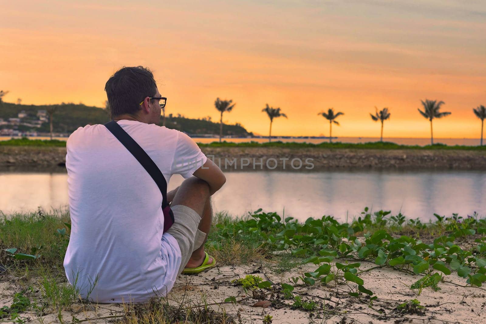 Upset man sitting at beach and watching sunset in tropics of Vietnam