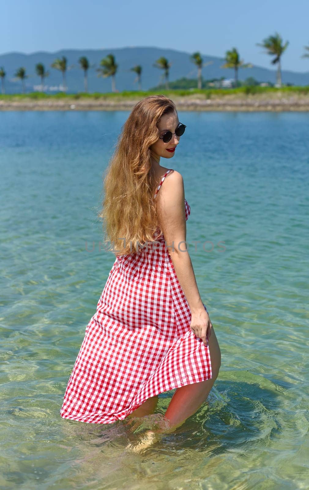 Bright blond young woman standing in sea in summer