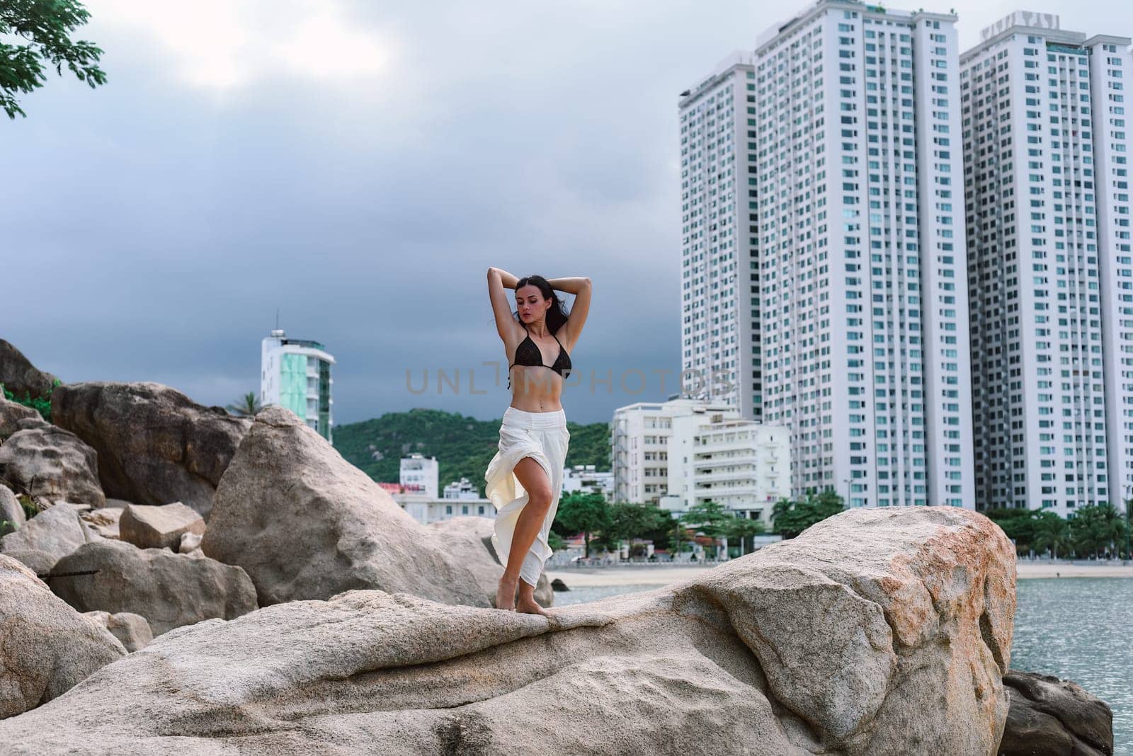 Young ukrainian woman in bikini sitting against cityscape of Nha Trang, Vietnam