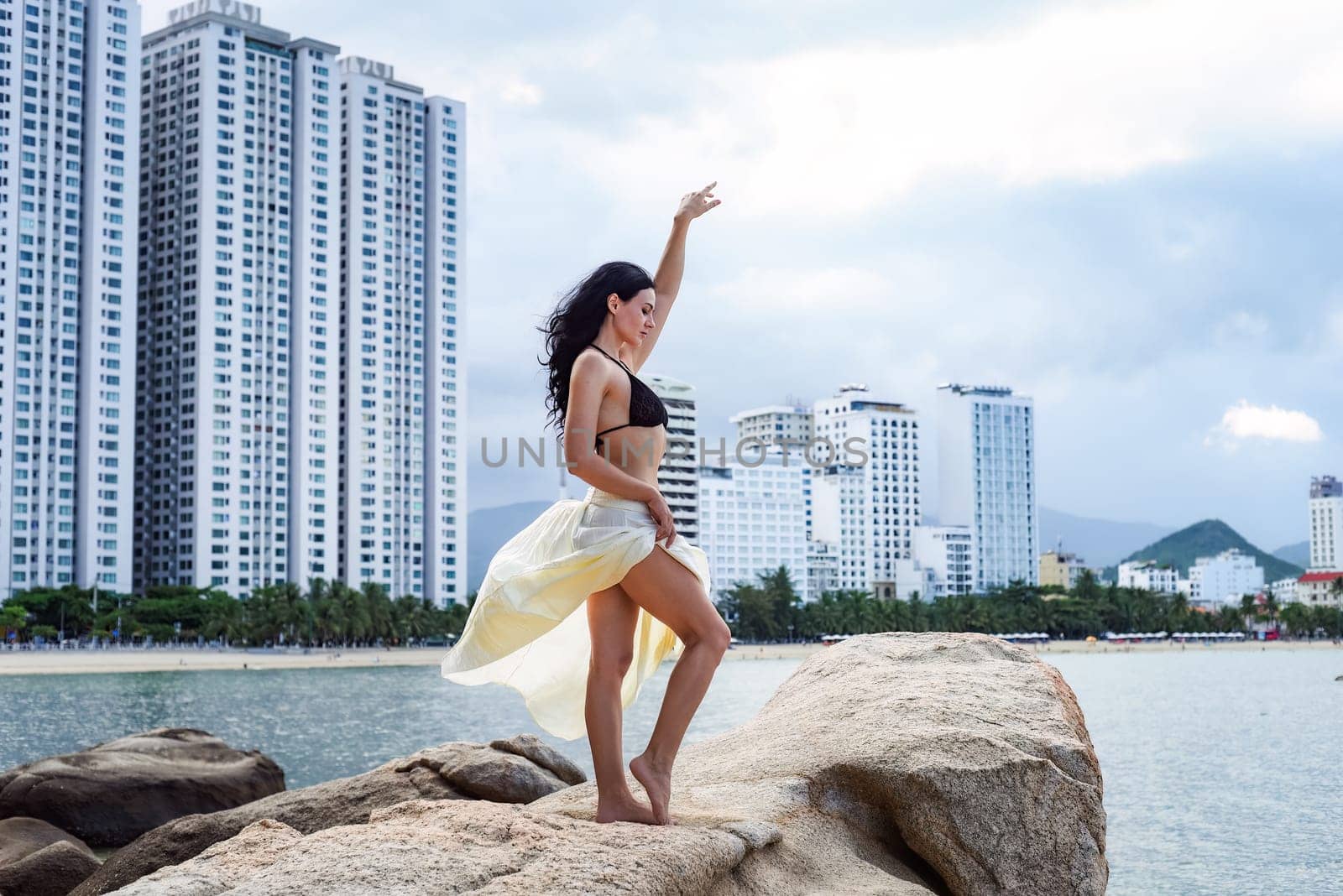 Young ukrainian woman in bikini sitting against cityscape of Nha Trang, Vietnam