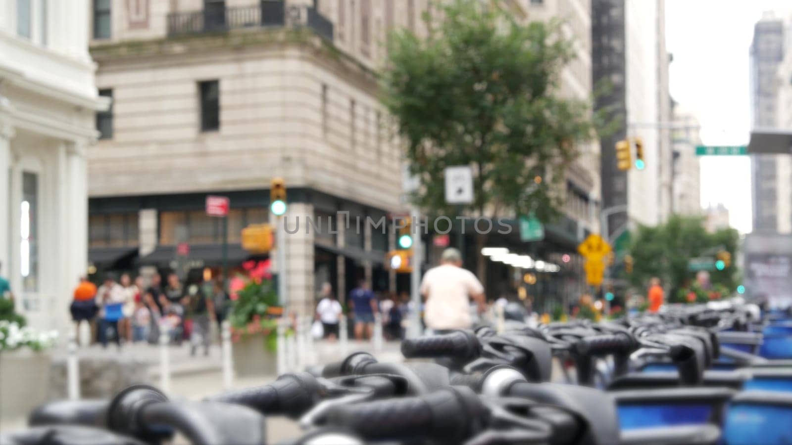 New York City Manhattan Downtown street or Midtown avenue crossroad intersection. Urban road traffic in USA. Defocused people pedestrians in United States. Blue rental bikes, sharing bicycles station.