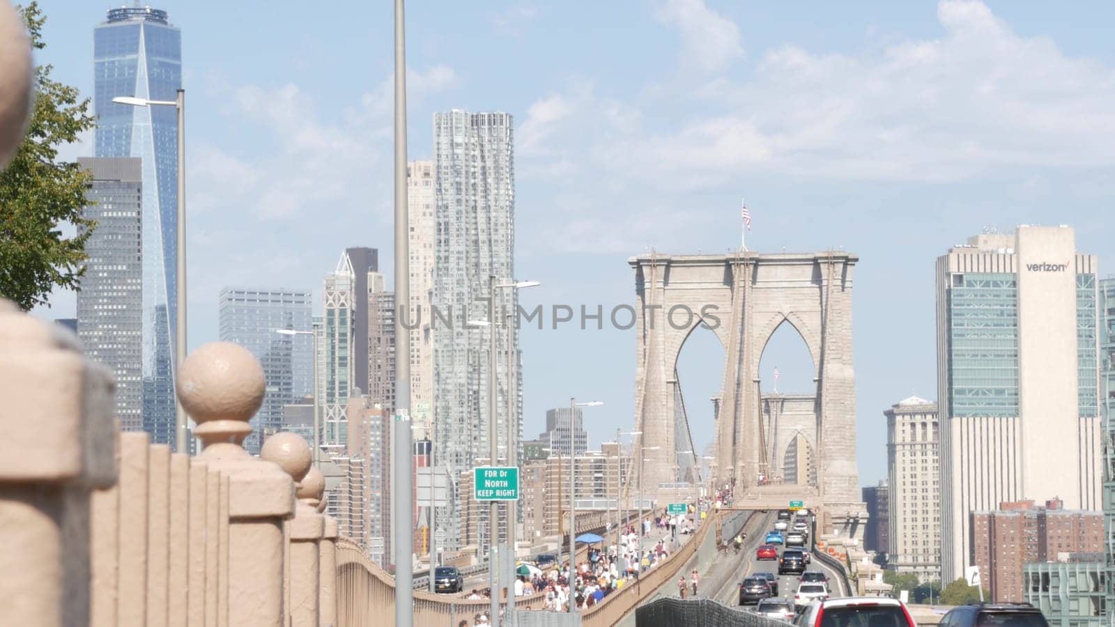 New York City, United States - 3 Sept 2023: Cars on Brooklyn Bridge from Manhattan downtown. Financial district skyline cityscape. Road traffic, people, architecture. World Trade Center skyscraper.