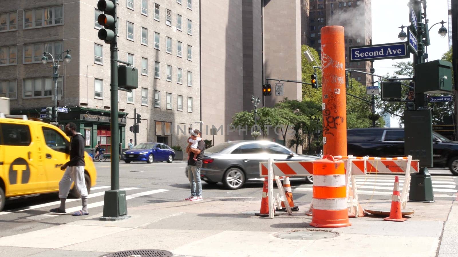 New York City, United States - 4 Sept 2023: Manhattan Midtown East 42 street, 2 avenue crossroad intersection. Urban road car traffic in USA. People, pedestrians on zebra. Yellow taxi cab. Smoke stack