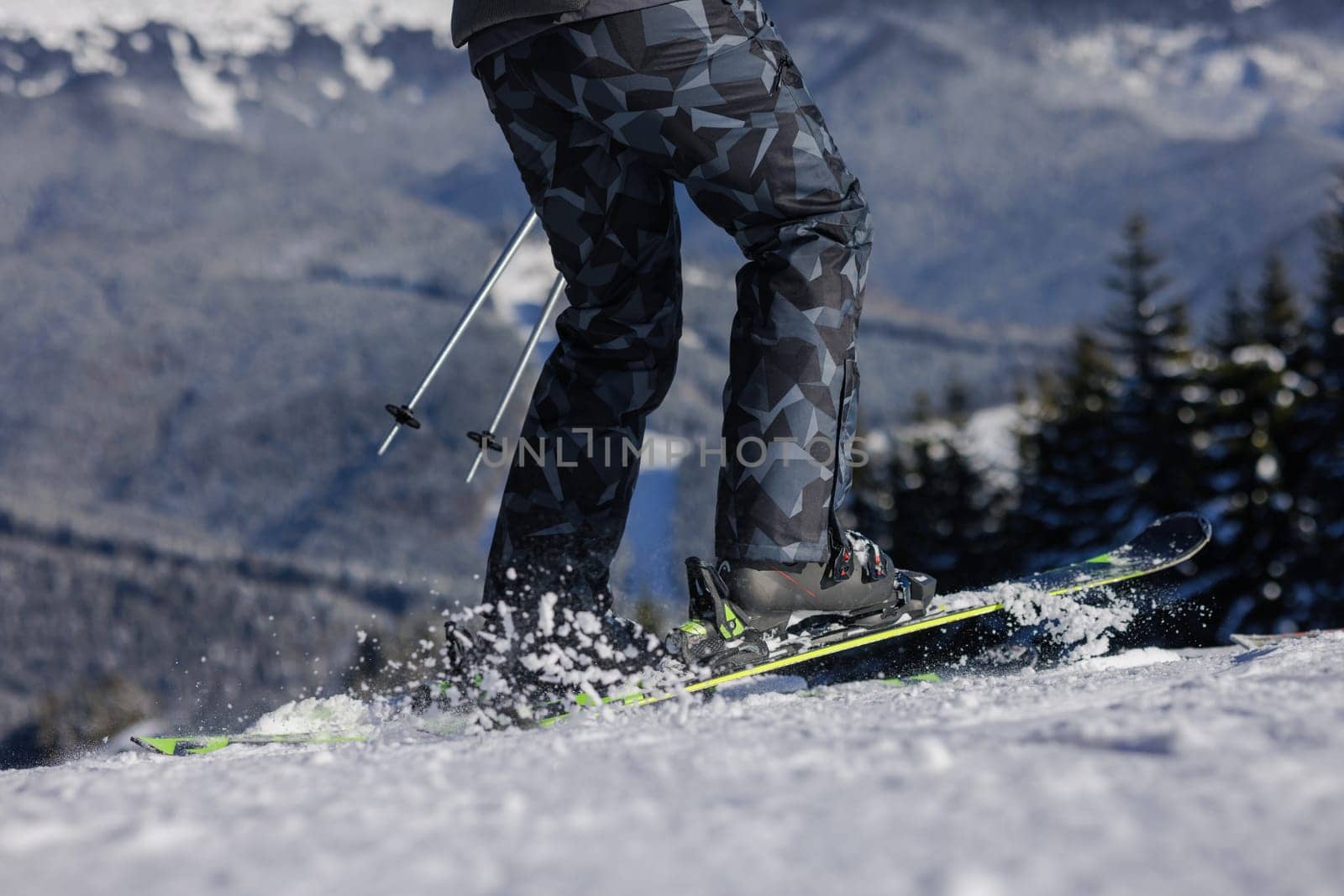Close-up of skier's legs and flying snow from under skis, ski tour. View from below. Winter sports concept,