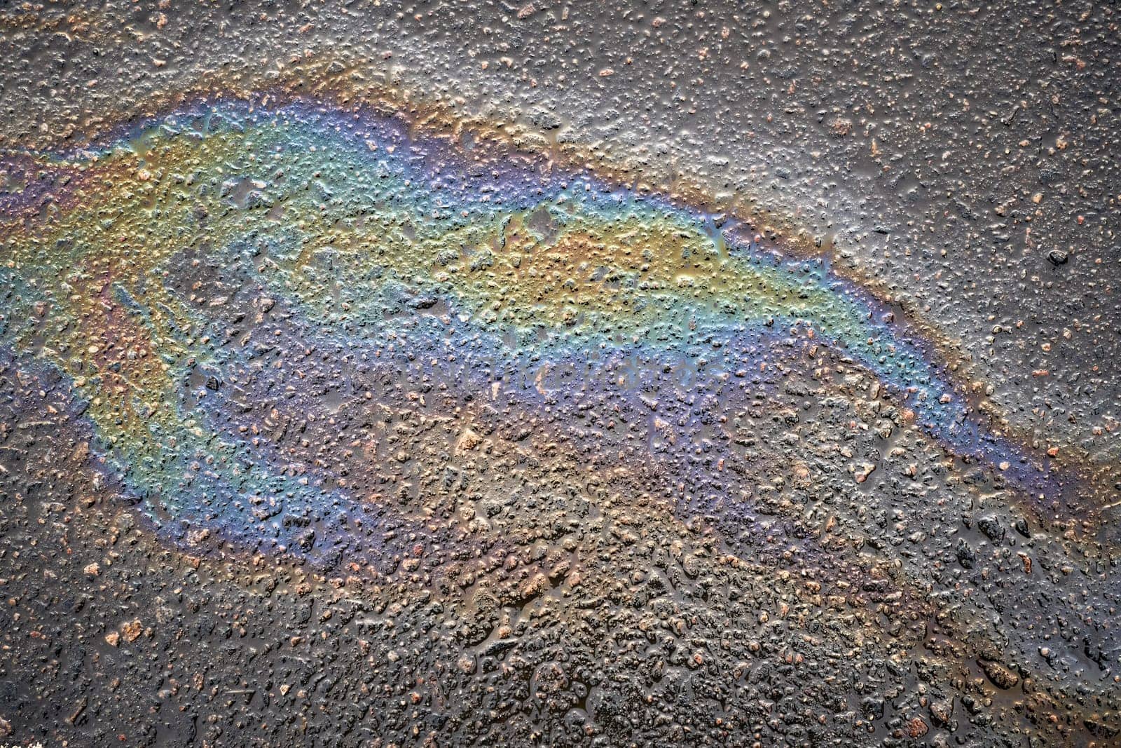Close-up of vibrant oil spills on asphalt, highlighting the rich colors and textures that form an engaging background