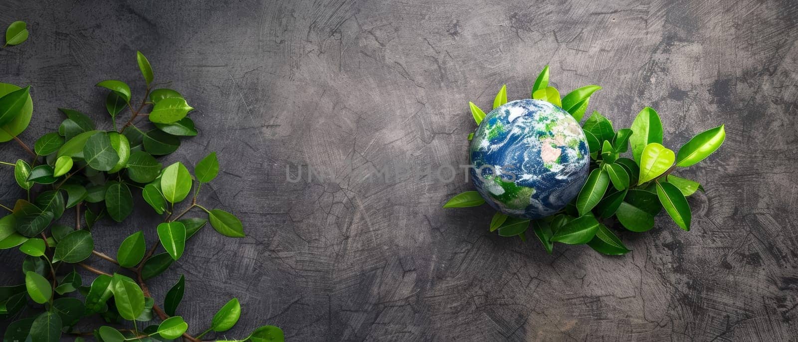 A vibrant globe surrounded by fresh green leaves rests against a textured gray backdrop, symbolizing nature's embrace and environmental care