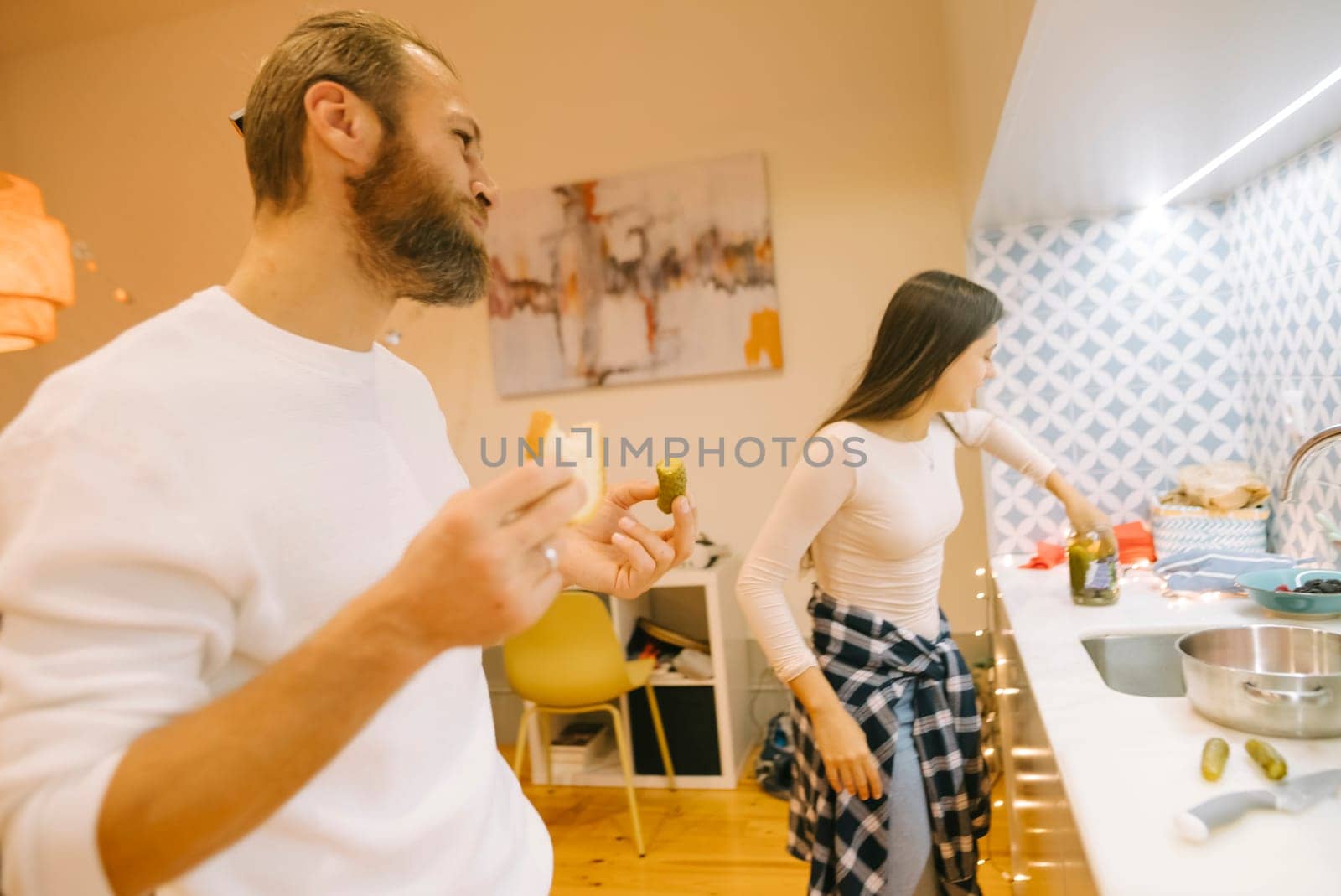 A couple enjoys cooking together in their cozy kitchen, showcasing a relaxed and intimate atmosphere of love