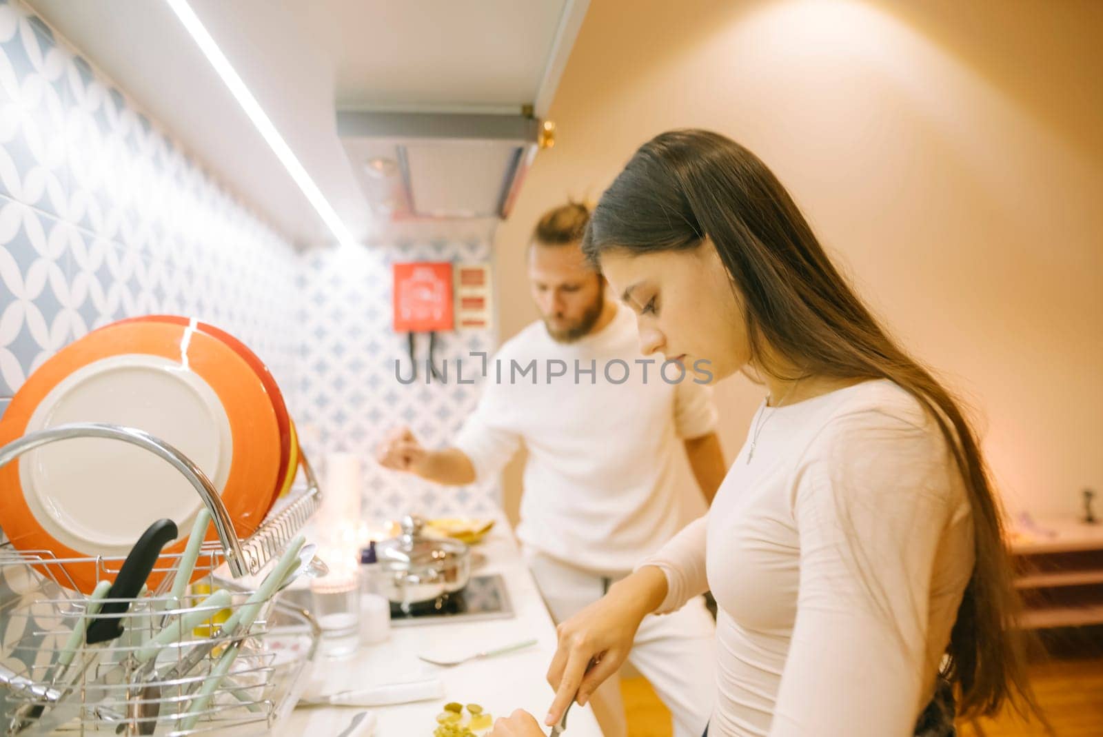A couple collaborates in a modern kitchen to cook a delicious meal, showcasing teamwork and culinary skills