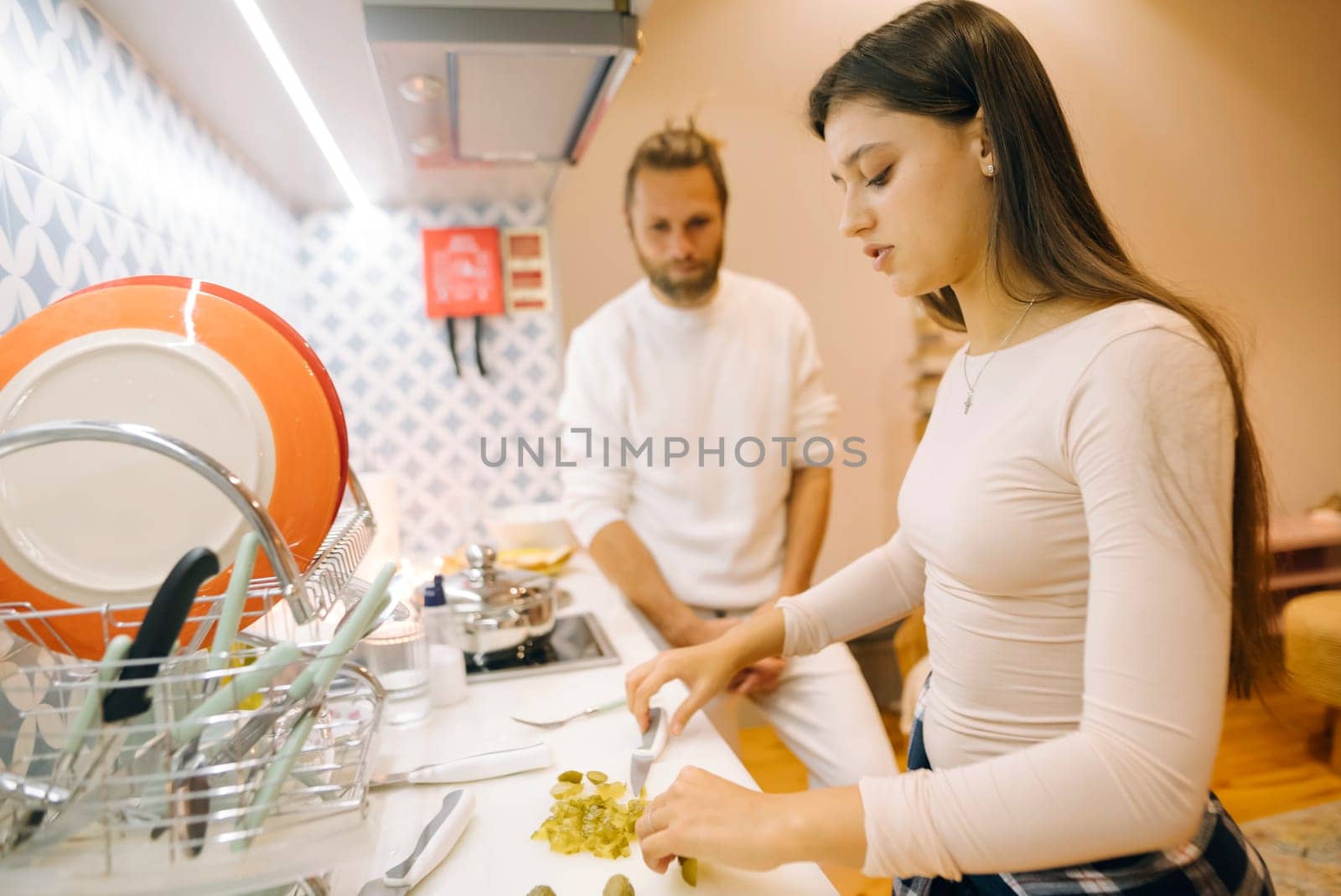 In a cozy kitchen filled with warmth, a couple joyfully cooks together, preparing a delicious meal for sharing