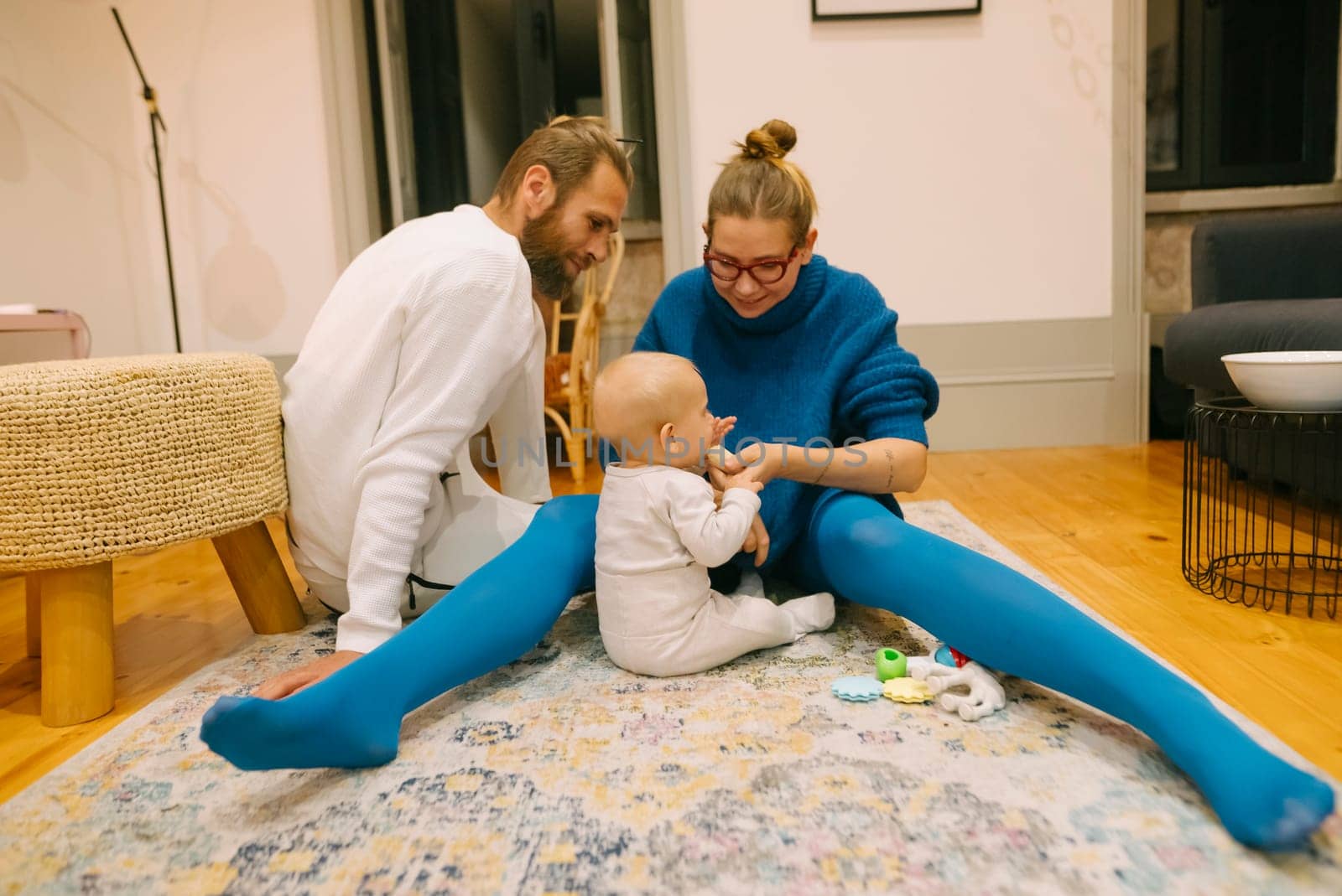A joyful family enjoys playtime on a cozy rug, engaging with their adorable baby in a relaxed setting