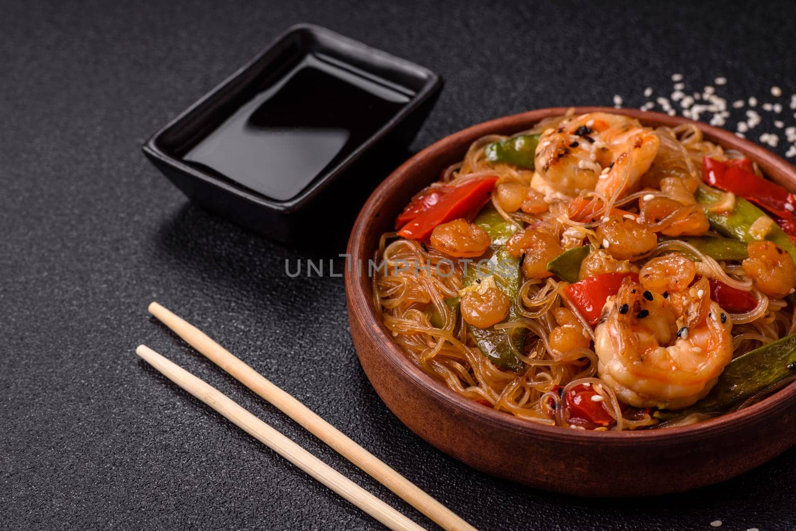 Glass noodles with shrimps and seafood, vegetables, spices and soy sauce on dark concrete background