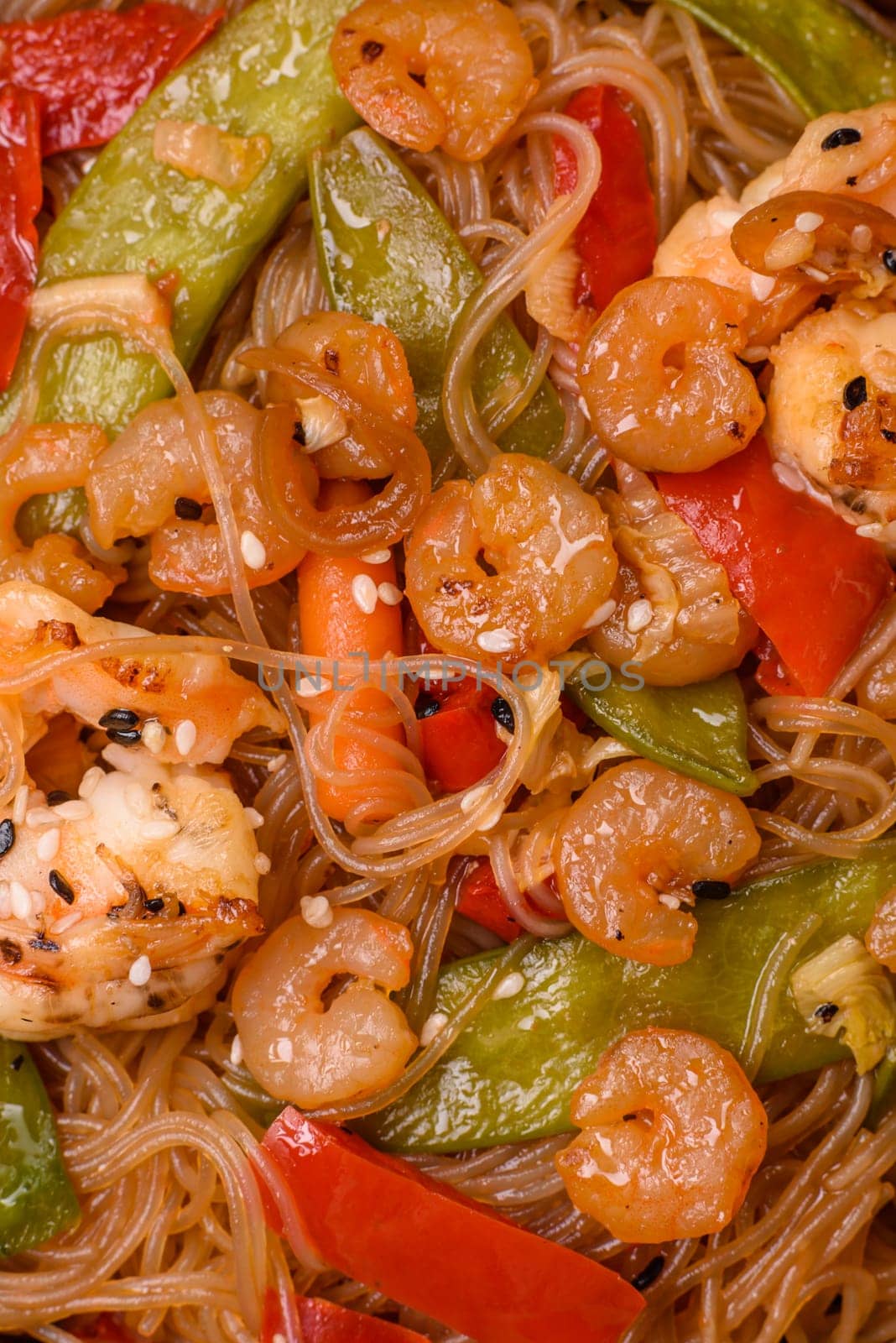 Glass noodles with shrimps and seafood, vegetables, spices and soy sauce on dark concrete background