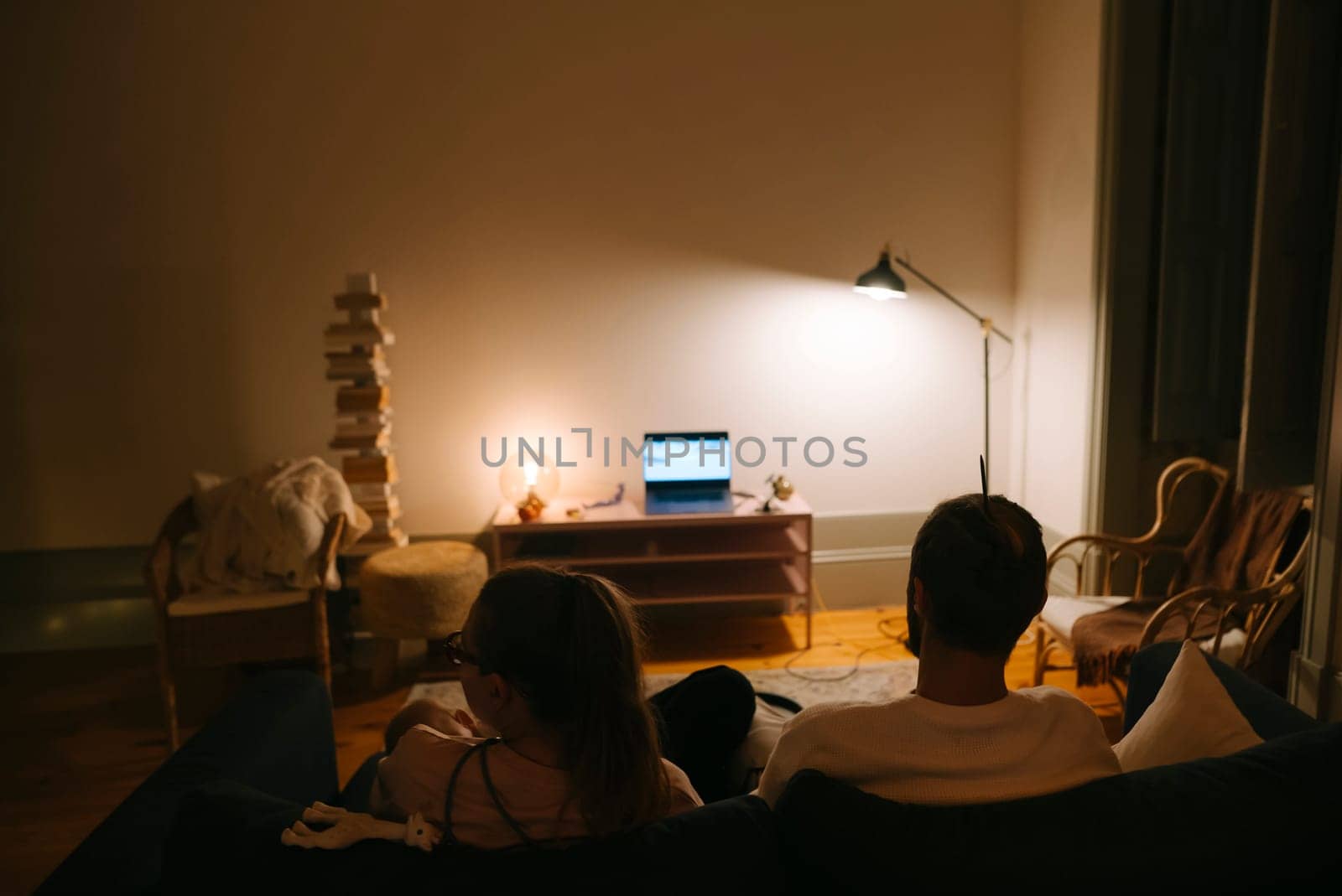 A couple happily enjoys a cozy movie night at home, nestled in soft lighting and an inviting, relaxed atmosphere