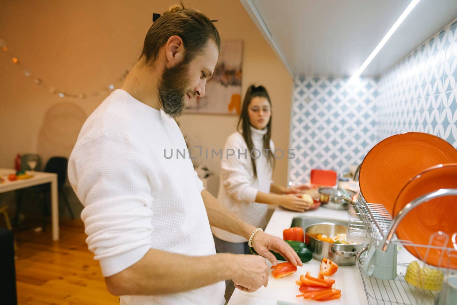 A couple shares a joyful and fun experience cooking together while preparing fresh vegetables in their stylish kitchen