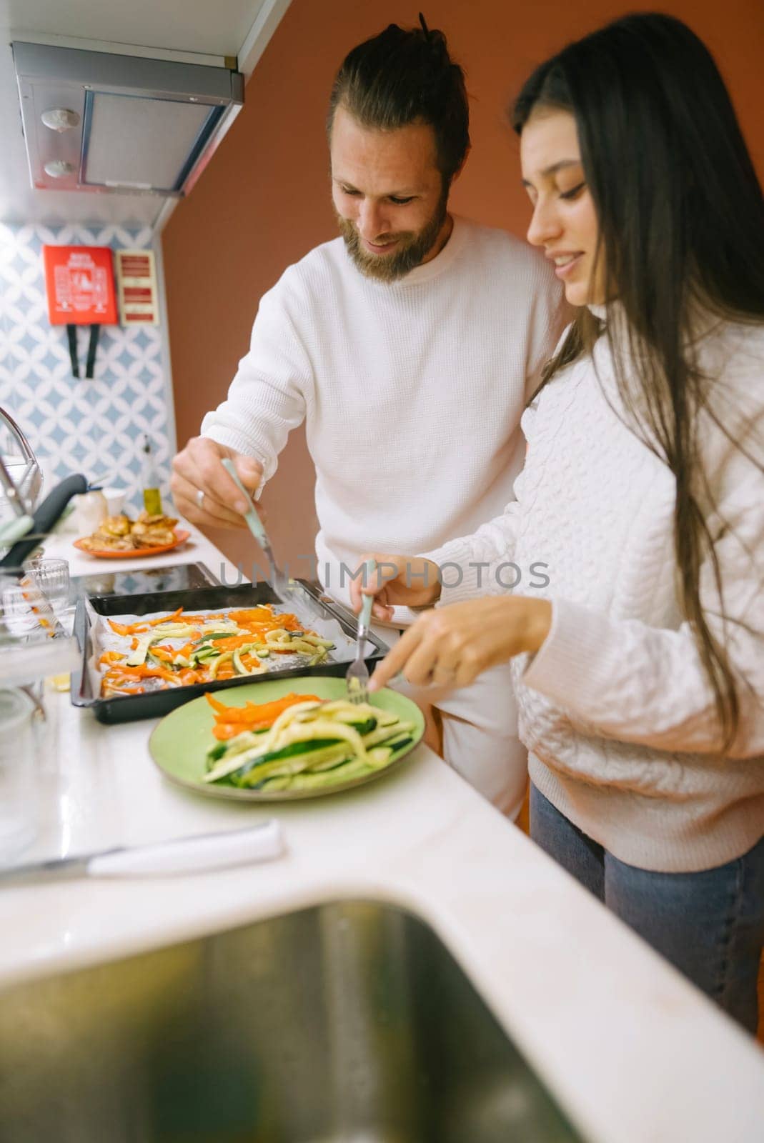 A happy couple joyfully cooking together in a warm kitchen, showcasing their love and passion for food