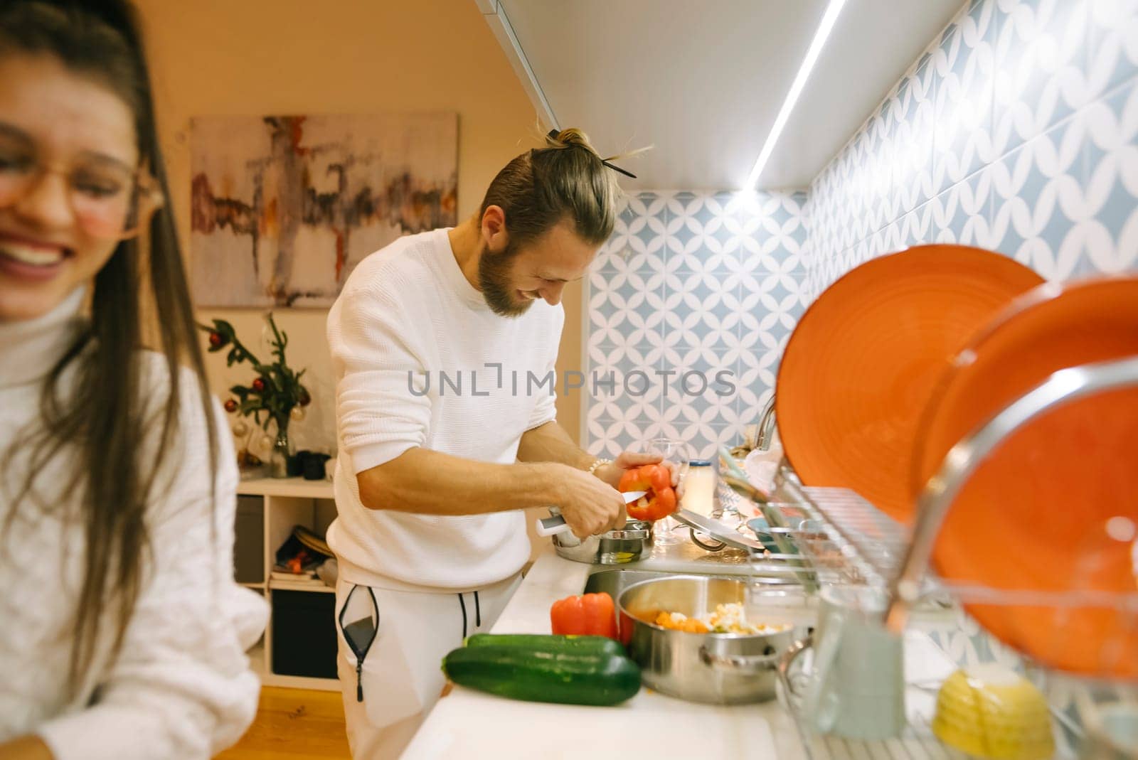A joyful couple prepares a meal together in a stylish kitchen, showcasing teamwork and culinary skills.