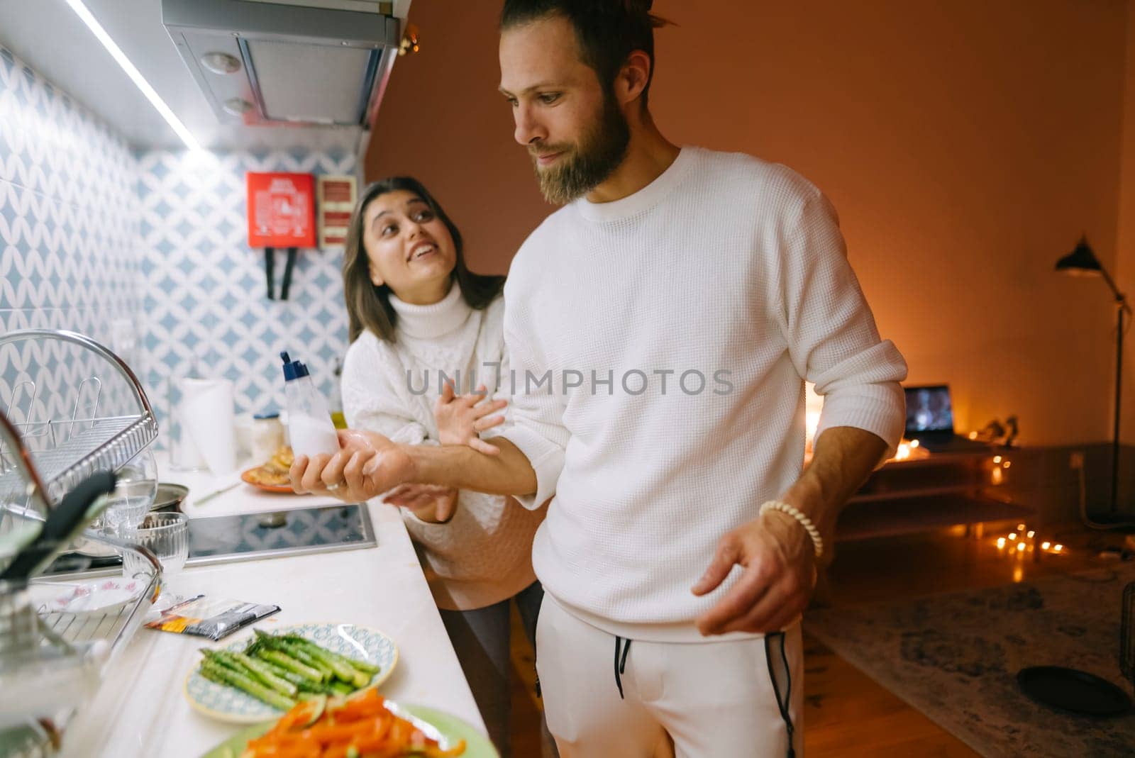 A couple enjoys a fun cooking session in their beautifully styled kitchen full of fresh ingredients