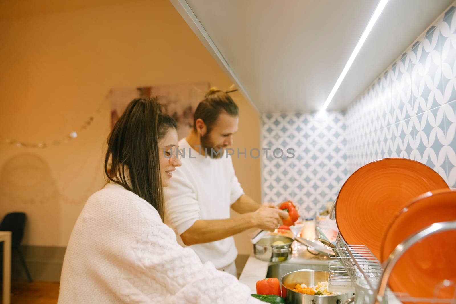 A couple happily enjoys cooking together in a stylish, welllit kitchen, creating cherished memories together