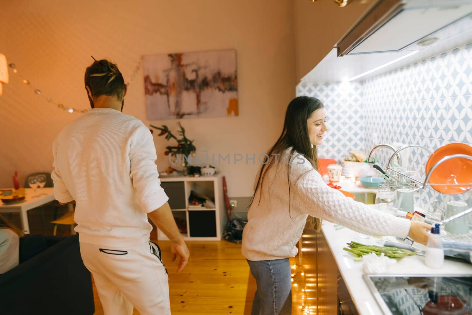 A lovely couple shares enjoyable quality time while washing dishes together in a cozy, modern kitchen setting