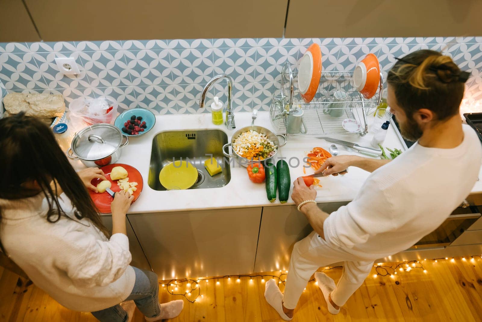 A joyful couple cooks in a modern kitchen filled with fresh ingredients to prepare a delightful meal