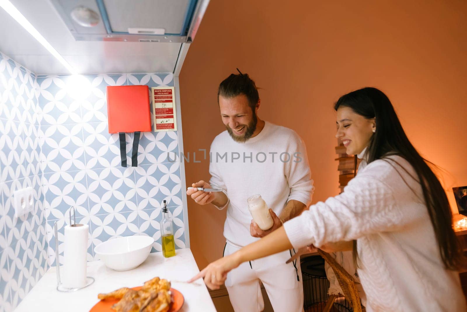 A joyful couple is happily preparing a delicious meal together, relishing their quality time in a stylish kitchen