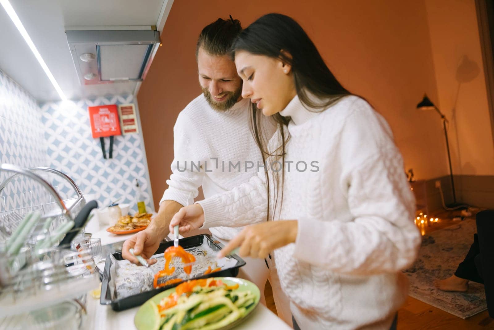 A couple happily enjoys cooking delicious meals together in a warm, inviting, and cozy kitchen setting
