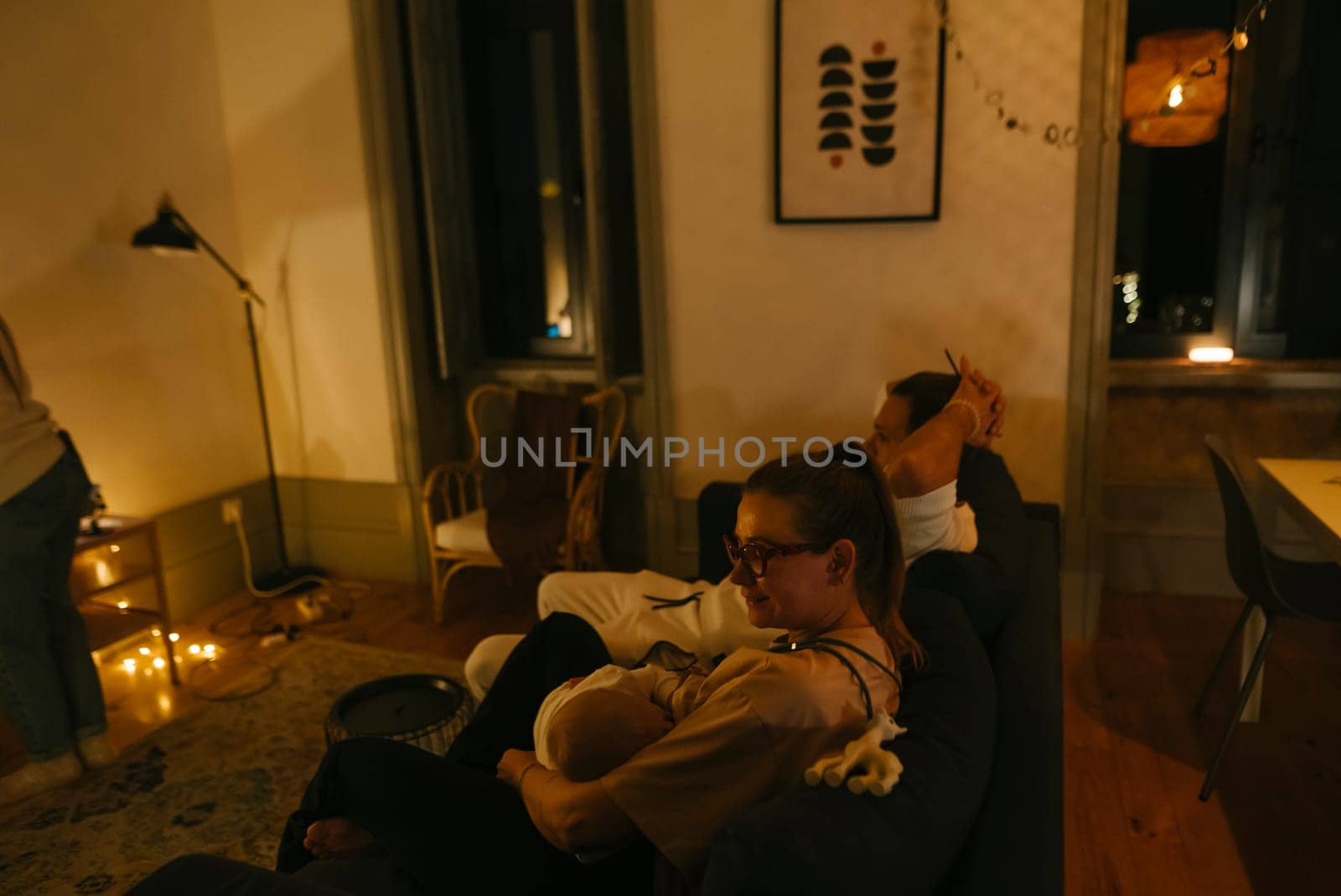 A warm and intimate moment encapsulating a beautiful family evening with their newborn in a cozy, modern living space