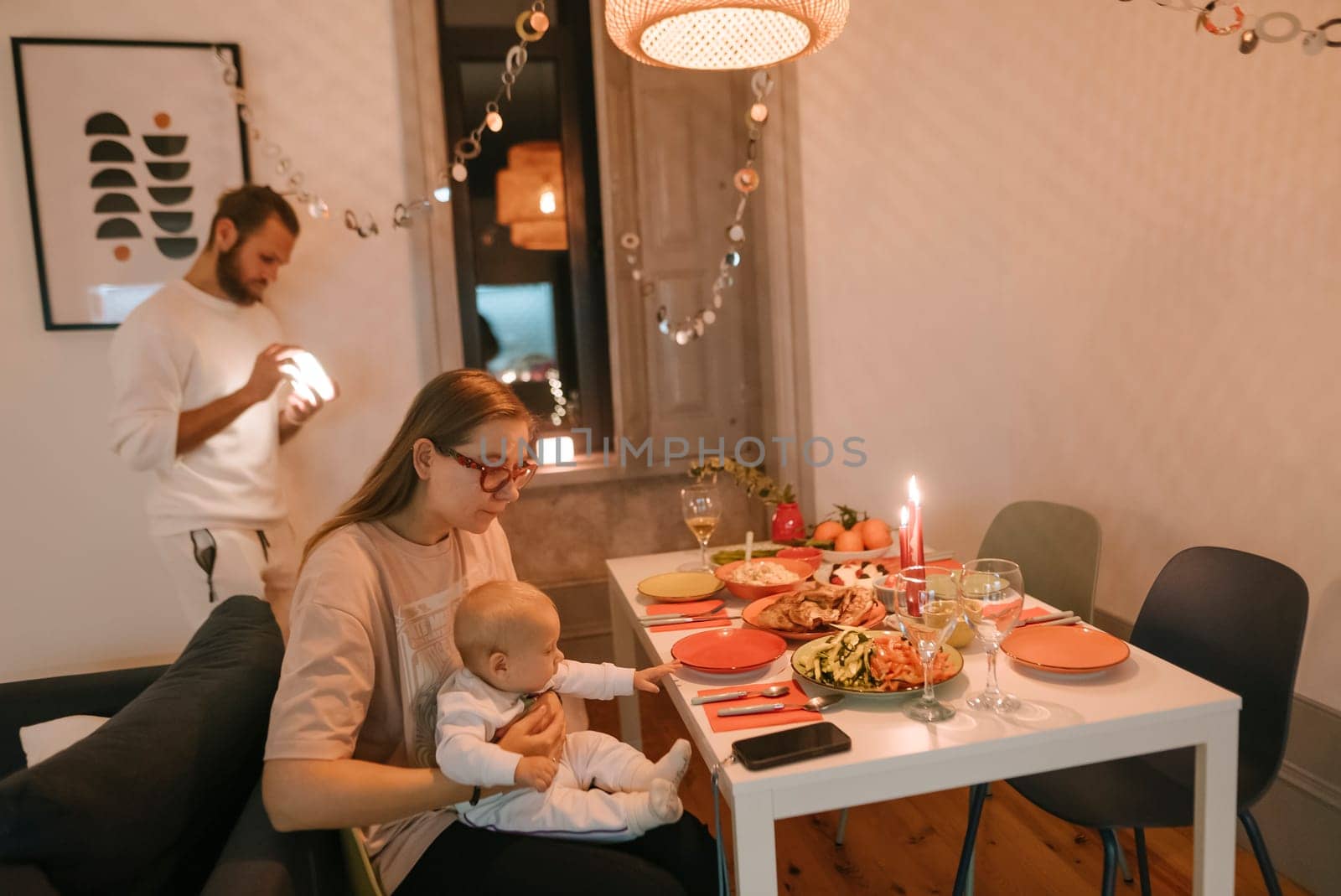 A warm family dinner scene featuring parents and their baby, decorated dining table, and cozy ambiance.