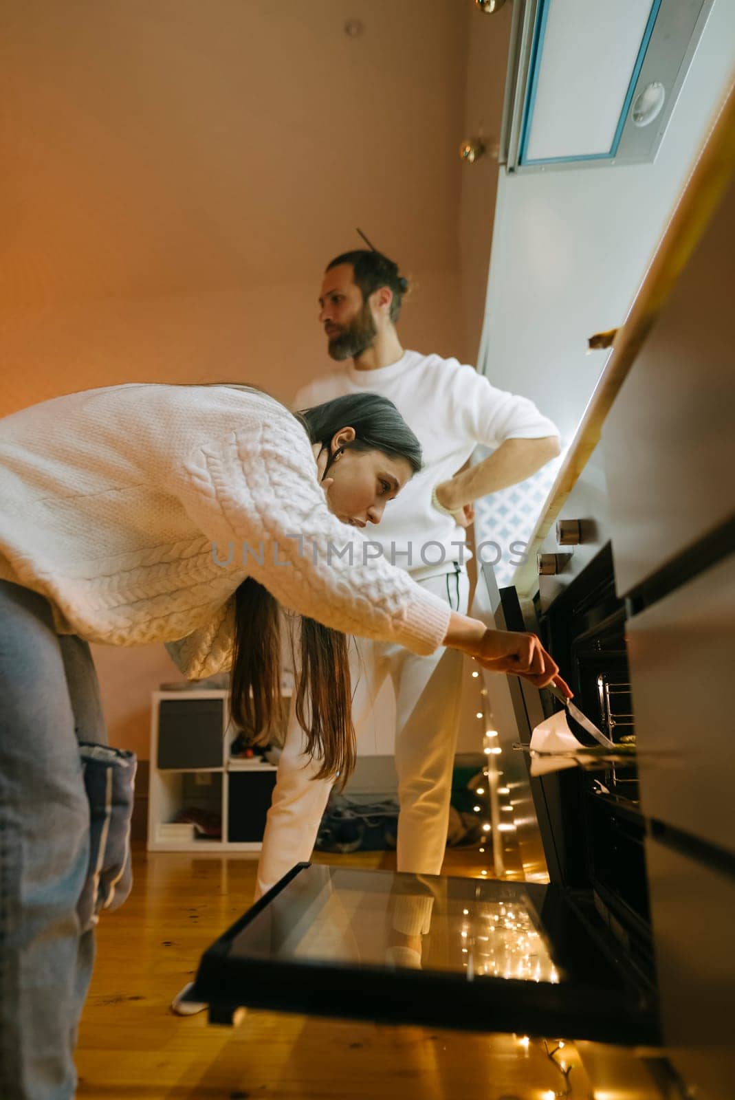 A couple joyfully cooks together in their modern kitchen, showcasing teamwork and genuine affection
