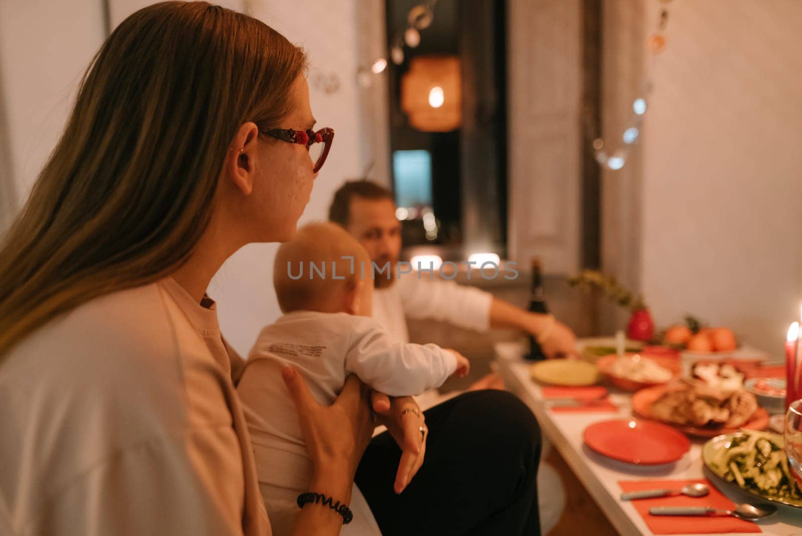 A warm and inviting family dinner setting that features a lovely baby, deliciously arranged food, and a cozy ambiance