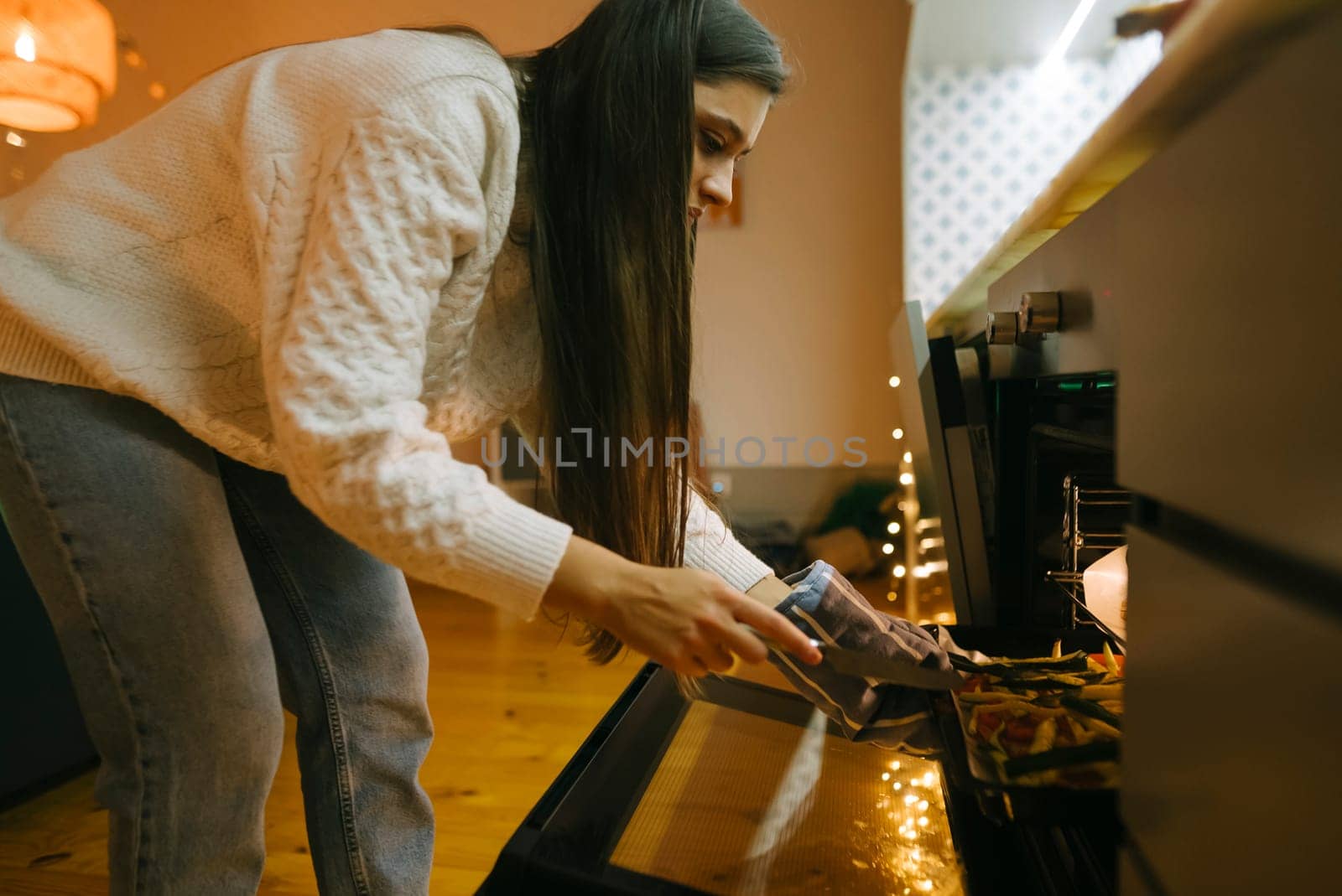 A woman pours fresh, colorful ingredients into the oven in a stylish kitchen that radiates comfort and elegance
