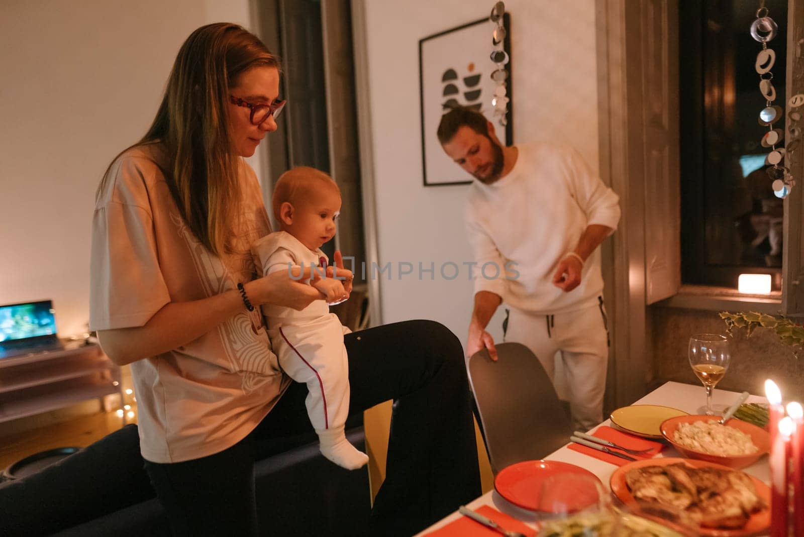 A family enjoys a cozy dinner gathering with their baby, surrounded by delicious food and warm ambiance.