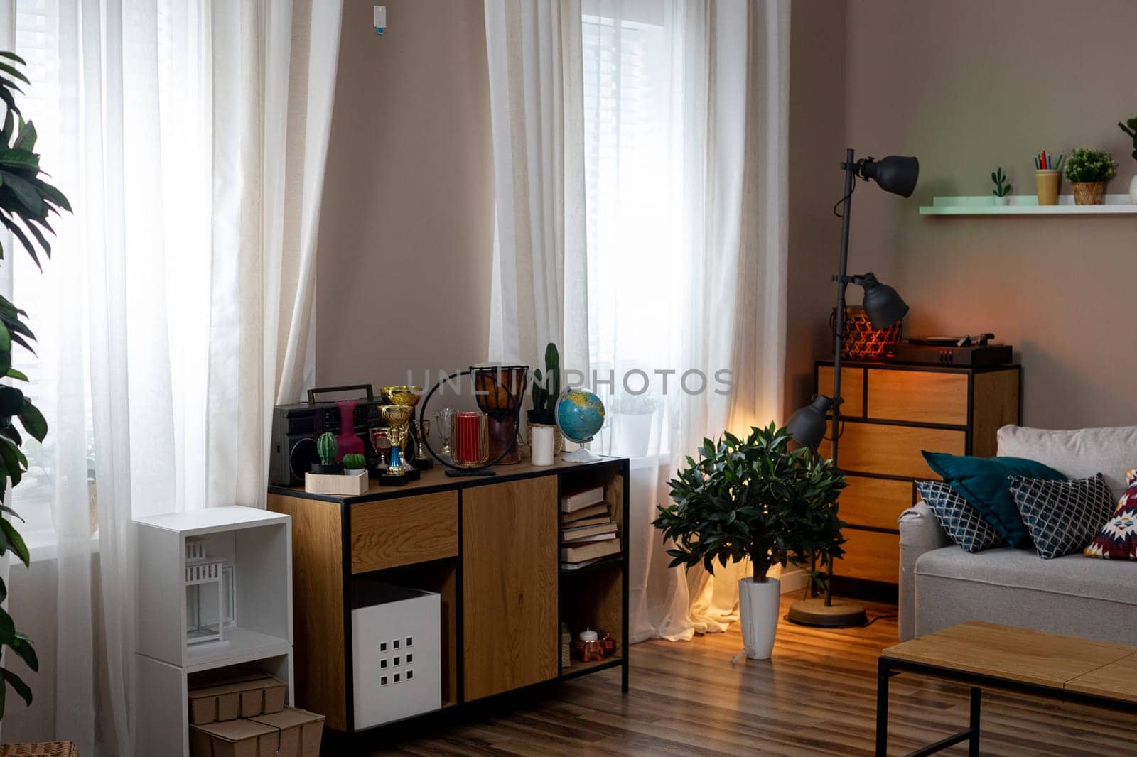 A stylish modern living room designed with ample natural light, vibrant plants, and sleek, contemporary decor