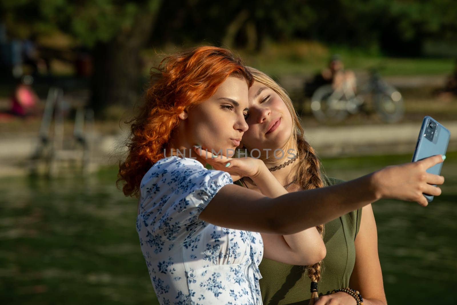 Two stylish women beautifully capture a joyful moment by a serene pond, showcasing their deep friendship